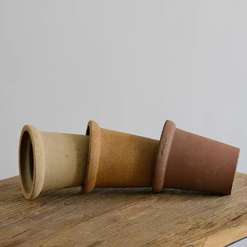 Set of 6-inch terracotta pots in natural tones. Sturdy clay planters with drainage holes for plants. Simple design with a rustic touch.