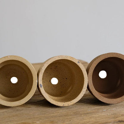 Bottom view of three 4-inch carry cup terracotta pots in earthy tones, each with a drainage hole. Ideal for small plants, promoting healthy root growth.