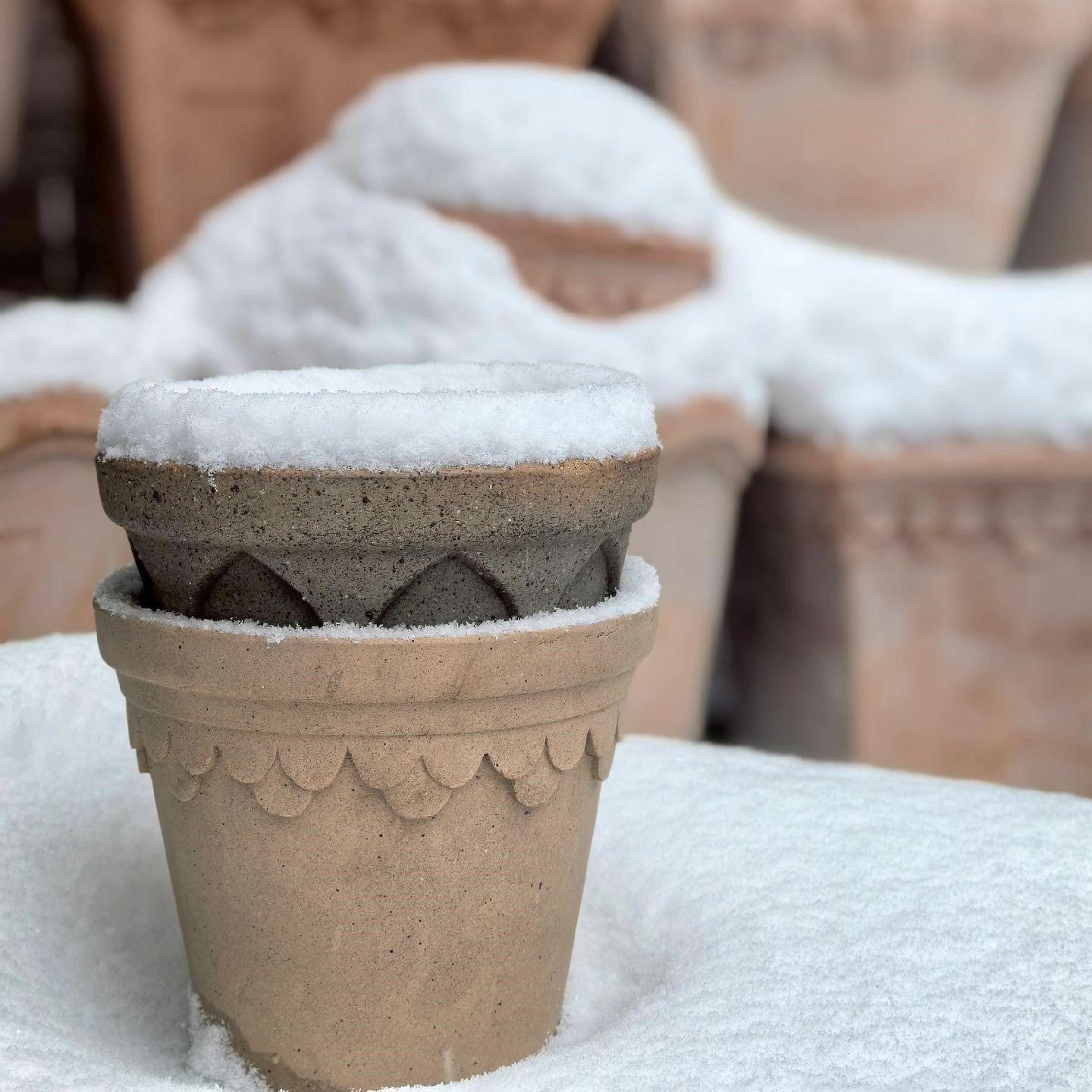 6-inch brown terracotta flower pot with scalloped edge, partially covered in snow, stacked with another pot, showcasing rustic charm.