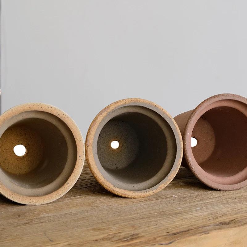 Set of 6-inch clay planters in earthy tones with drainage holes. Sturdy design, perfect for small plants. Simple, durable terracotta flower pots.