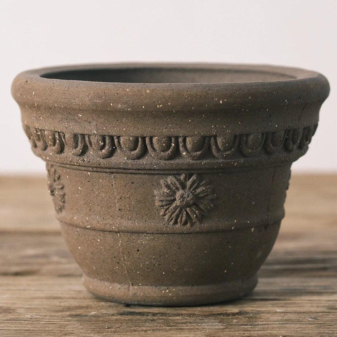 7-inch dark brown carved terracotta planter with flower pattern. Durable clay pot with a rustic design for medium plants.