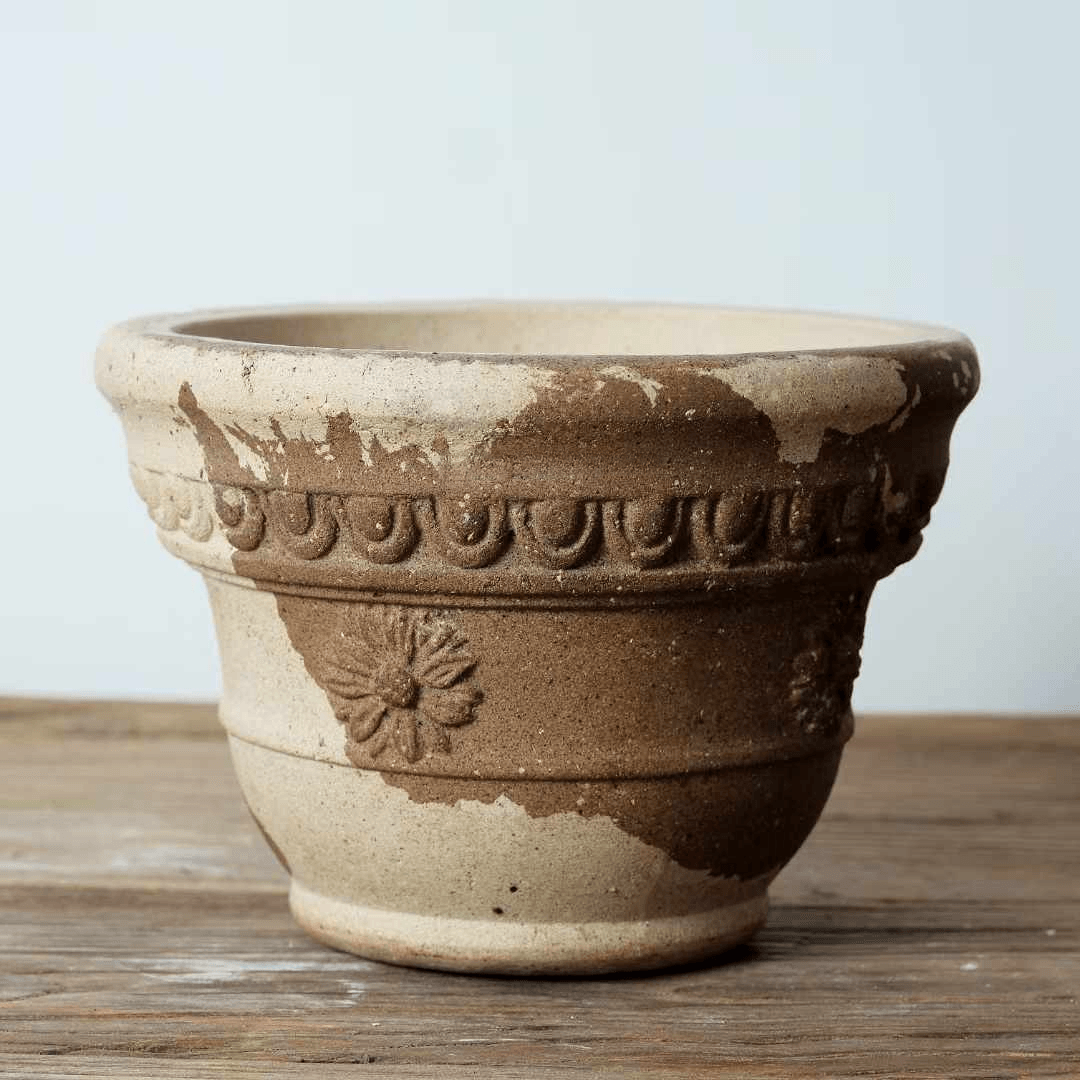 7-inch two-tone terracotta planter with floral design. Rustic clay pot with a classic shape, featuring natural brown and beige tones.