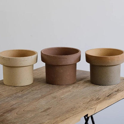 Set of 7-inch rustic cone-shaped ceramic planters in beige, brown, and earthy hues, ideal for medium indoor plants; sturdy stoneware pots on a wooden table.