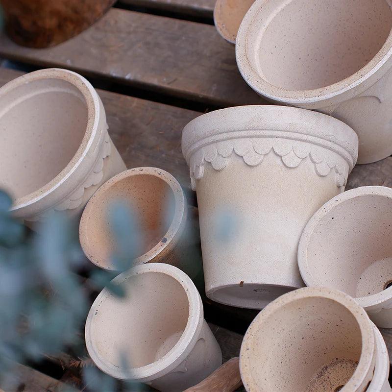 Assorted white clover-style terracotta pots in multiple sizes, featuring decorative scalloped edges. Ideal for showcasing a range of plants and enhancing indoor decor.