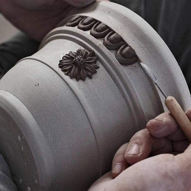 Handmade 7-inch sculpted clay planter with floral design, ideal for small plants. Rustic, durable ceramic pot in earthy tones.