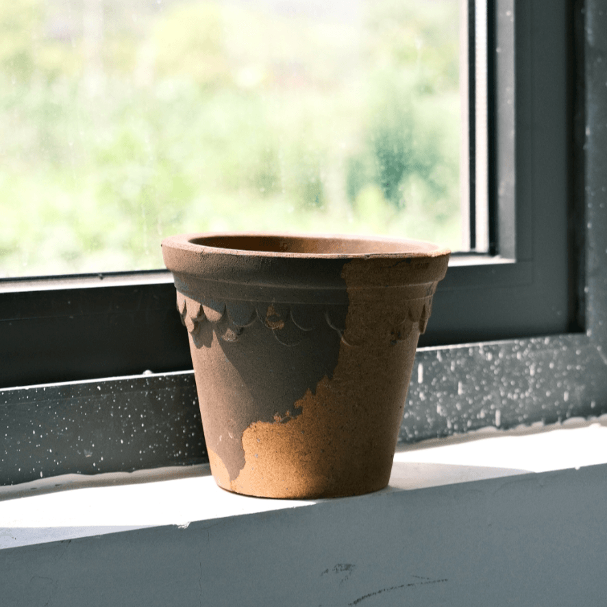 Latte and brown ceramic container with scalloped edge, featuring a rustic two-tone design, placed on a windowsill in natural light.