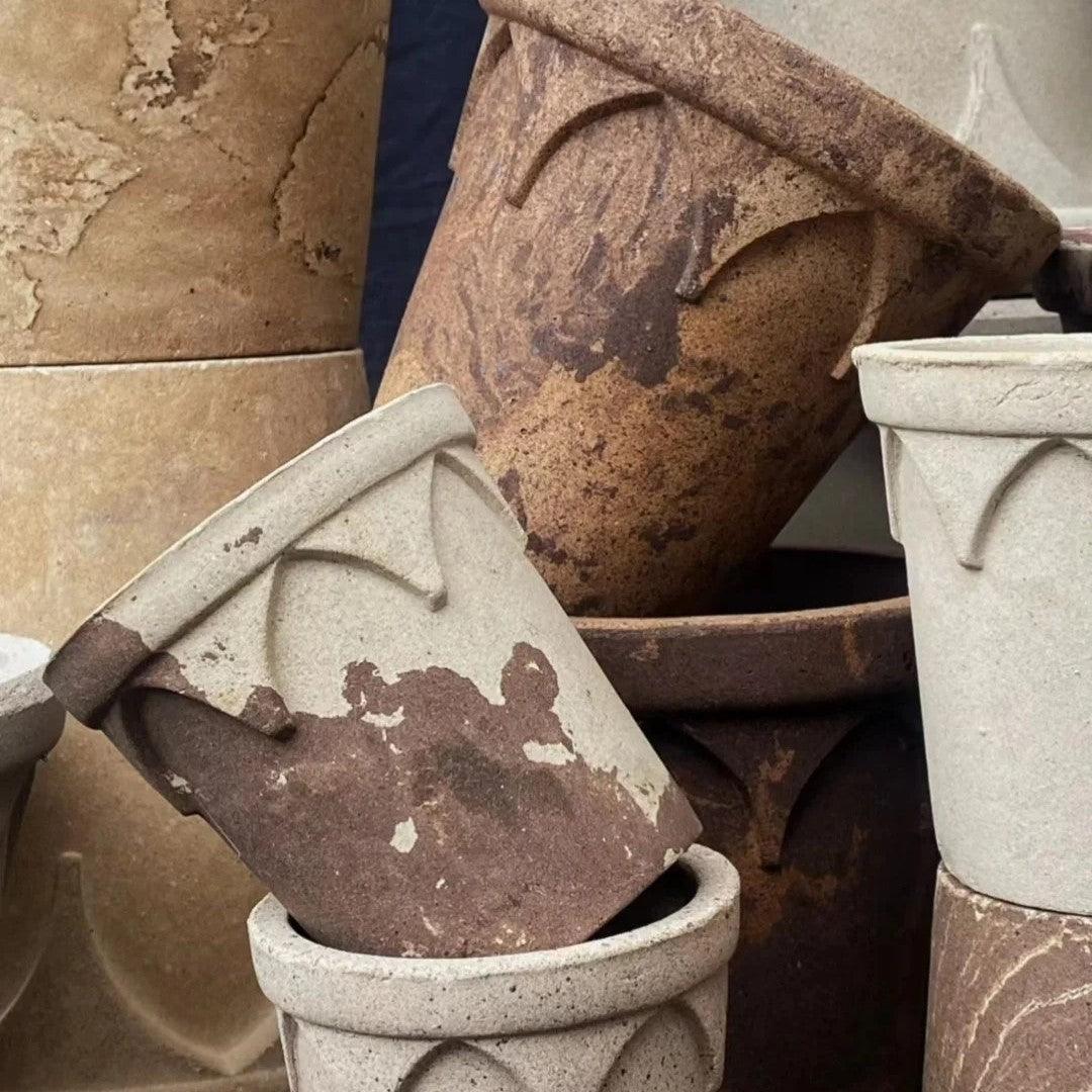 Various sizes of rustic clay crown planters in earthy tones, with textured arches; ideal for different indoor plants, offering a natural ceramic look.