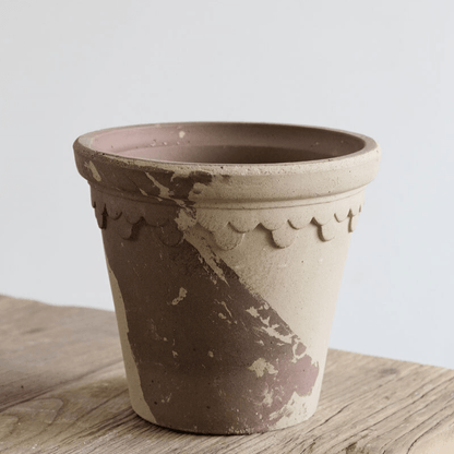 Rustic two-tone garden pot with scalloped detail in earthy beige and brown shades, displaying a weathered, artisan finish on a wooden surface.