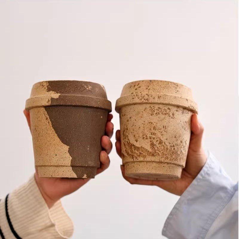 Pair of 4-inch coffee cup-shaped clay pots in rustic beige and brown tones, held side by side, displaying a natural, textured finish.